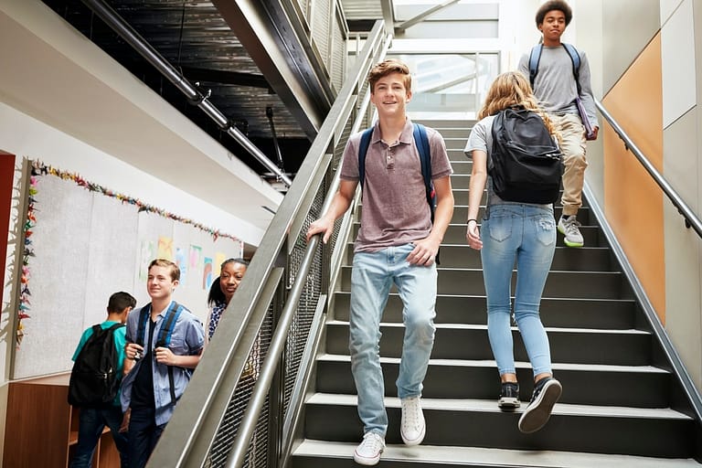 Students Walking Down Stairs In Busy College Building